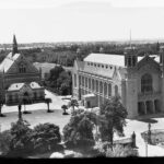 Image: A black and white aerial photograph shows two large stone halls surrounded by gardens