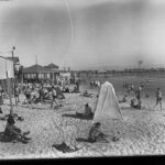 Image: People on a beach with a jetty in the background