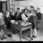 Image: children standing around woman checking young boy