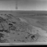 Image: High sand dunes with a jetty in the background