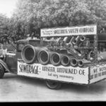 Image: truck carrying large pipes and sewer signage