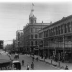 Image: black and white photo of street lined with three and four storey buildings