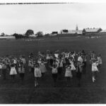 Image: large group of children on oval with arms stretched forwards