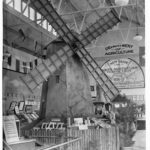 Image: A windmill is on display inside of a tall building.  There is a sign in the background that reads: Department of Agriculture