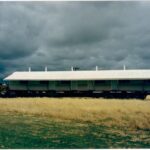 Image: large curved tin building being towed on the back of a truck