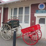 Image: Restored horse-drawn cart outside of a historical society building.