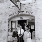 Group of people standing on door step of stone and brick building