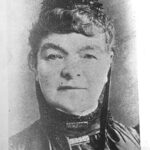 Image: Black and white headshot of woman wearing a fascinator