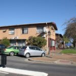 Image: suburban street with block of flats and several parked cars