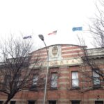 Image: top storey of red brick three-storey building, with three flags flying