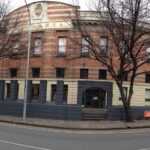 Image: panorama shot of a red brick building of three storeys, taken in winter with barren trees outside