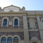 Image: A large, two-storey stone building with the words ‘Institute of Arts & Sciences’ painted on its front façade