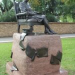 Image: bronze statue of seated woman with books