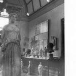 Image: a collection of marble statues arranged for display in a room with a vaulted ceiling.