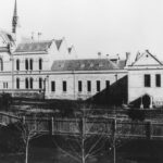 Image: the side view of a large stone building made up of four sections which step down a hill and become less elaborate the further they are from the street.