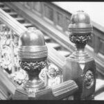 Image: A close up image of decorative carving on the newels (and the knobs that top them) of a large staircase