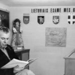 Man sitting in small archive room with pictures behind him