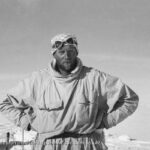 Man standing in snow with goggles on his head