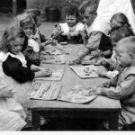 Image: several caucasian children sit around a wooden table playing with plasticine