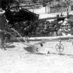 Image: photo of man pushing plow with letters to indicate the different parts of the plow