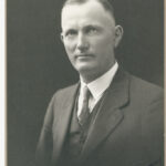 Image: Upper body portrait photograph of a man wearing a suit