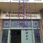 Image: garlands of crocheted violets hanging from building entrance