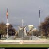 Image: a large fountain made of granite and aluminium featuring seated figures with birds and flanked by two flagpoles flying the Australian and Indigenous flags.