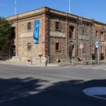 Image: Large stone building on corner with blue banner on closest wall.