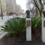 Image: Bronze busts of two men's heads in garden next to footpath