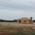 Image: Colour photo of an abandoned brick building in a field.