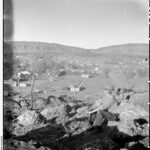 Image: man sitting on rocky outcrop overlooking township