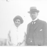 Image: man wearing hat and woman with boa pose for photograph