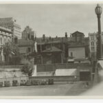 Image: a number of alterations and extensions to a large stone building spill down a hill.  Below these buildings is a carpark and an underground entrance for ambulanaces.