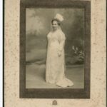 Image: black and white photo of woman standing in white dress and veil