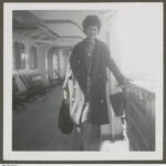 Image: Woman on a boat, posing for a photograph, holding onto the side rail