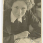 Image: Photographic portrait of a young woman in school uniform. She has a book open in front of her. The photo is inscribed in blue pen: "To Nanny, With Love, Barbara"