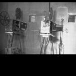 Image: Two film projectors of 1940s vintage stand in a projection room that is likely located within a cinema