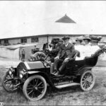 Image: Five well-dressed people sit in a sedentary automobile