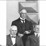 Image: Three middle-aged men in Edwardian attire pose for a photographic portrait