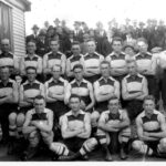 Image: A group of young Caucasian males in 1920s-era Australian Rules Football uniforms pose for a photograph