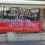 Image: large banner with message painted in yellow and white over a red and black background