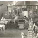 Image: interior of building with curved roof, people at game table