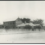 Image: a brick convent building behind a stone wall.