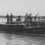 Image: A small motor launch with water cannons and the name ‘Fire Queen’ emblazoned on its bow sits stationary in a river