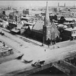 Image: aerial view of stone church with large steeple on street corner