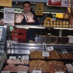 Image: man standing with large selection of raw chicken at market stall