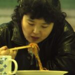 Image: woman eating noodles with chopsticks