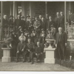 Image: Twenty-nine people, both men and women on the steps and verandah of a building