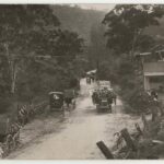 Image: old cards, dirt road, paddocks and hut