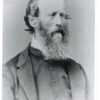 Image: a head and shoulders portrait of a man in three quarter profile. He is balding but has a long bushy beard.